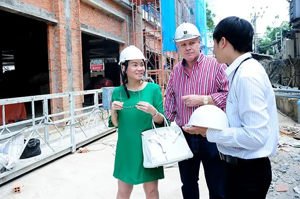 Ba người đội mũ bảo hộ trao đổi tại công trình đang xây