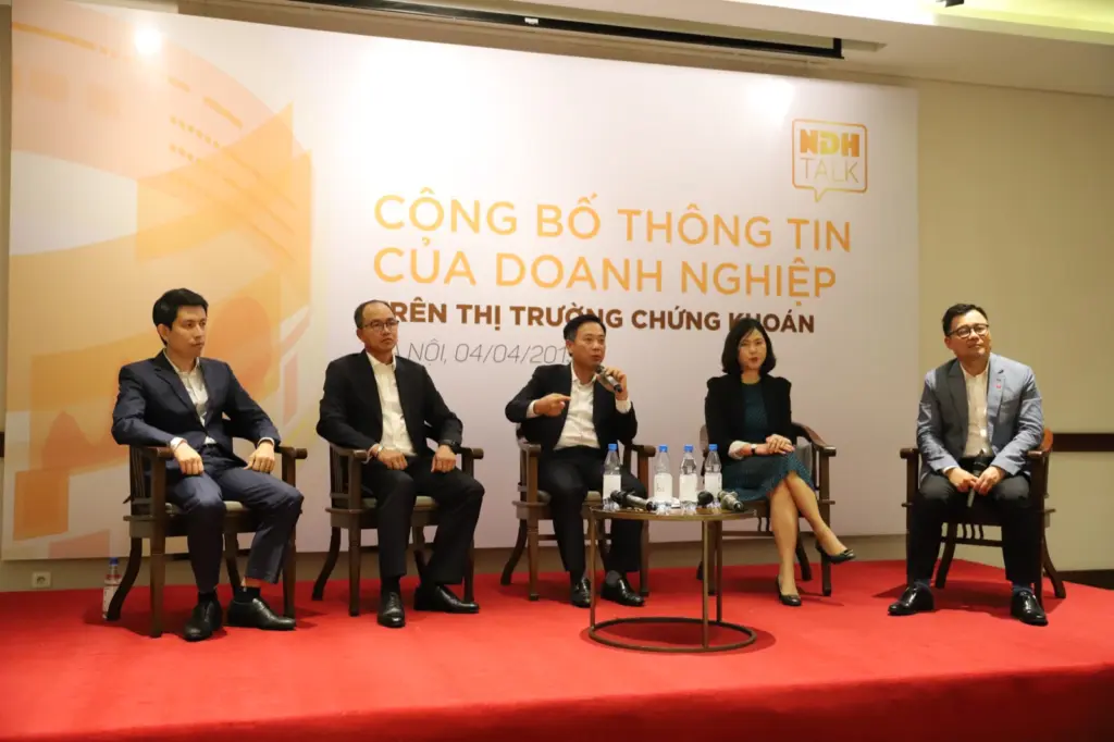 Năm diễn giả ngồi trên sân khấu toạ đàm NDH Talk, phông nền ghi “Công bố thông tin của doanh nghiệp trên thị trường chứng khoán”, Hà Nội ngày 4/4/2019.