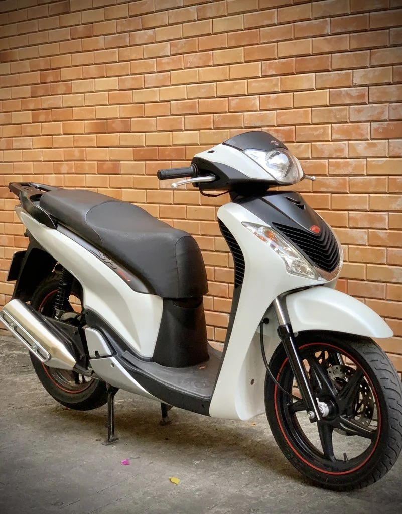 Xe Honda SH màu trắng dựng bên tường gạch