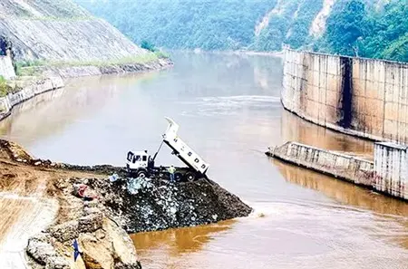 Công trình đập thuỷ điện bên dòng sông, máy móc thi công trên bờ