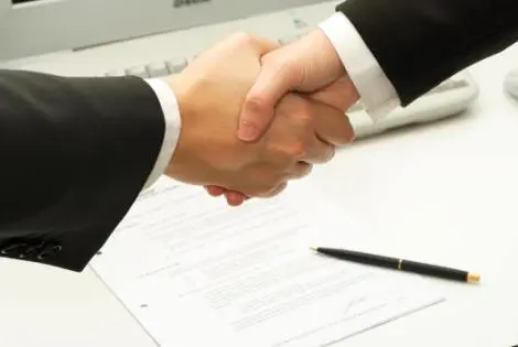 Hai người bắt tay trên bản hợp đồng đã ký