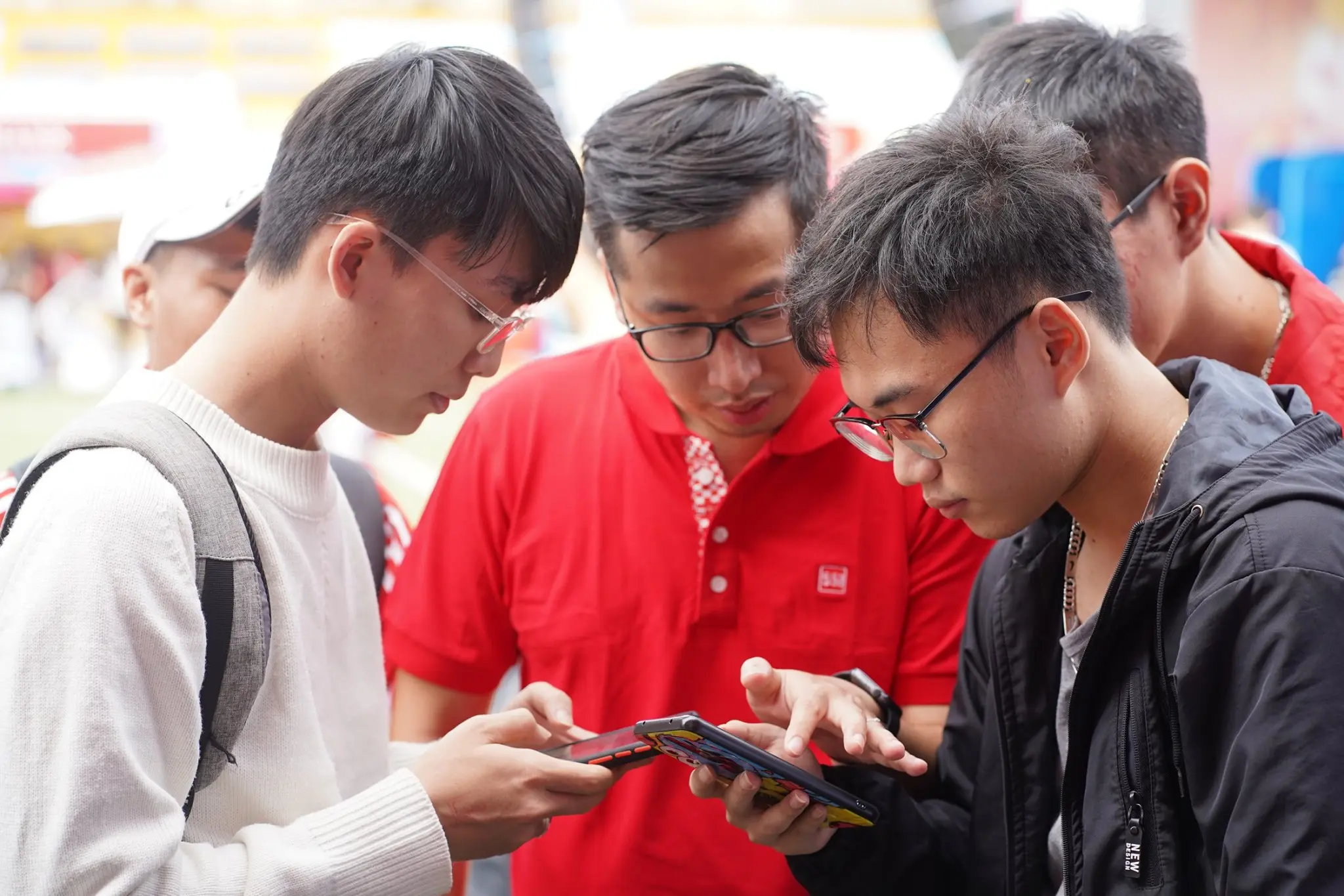 Ba bạn trẻ cùng xem điện thoại tại gian hàng SSI
