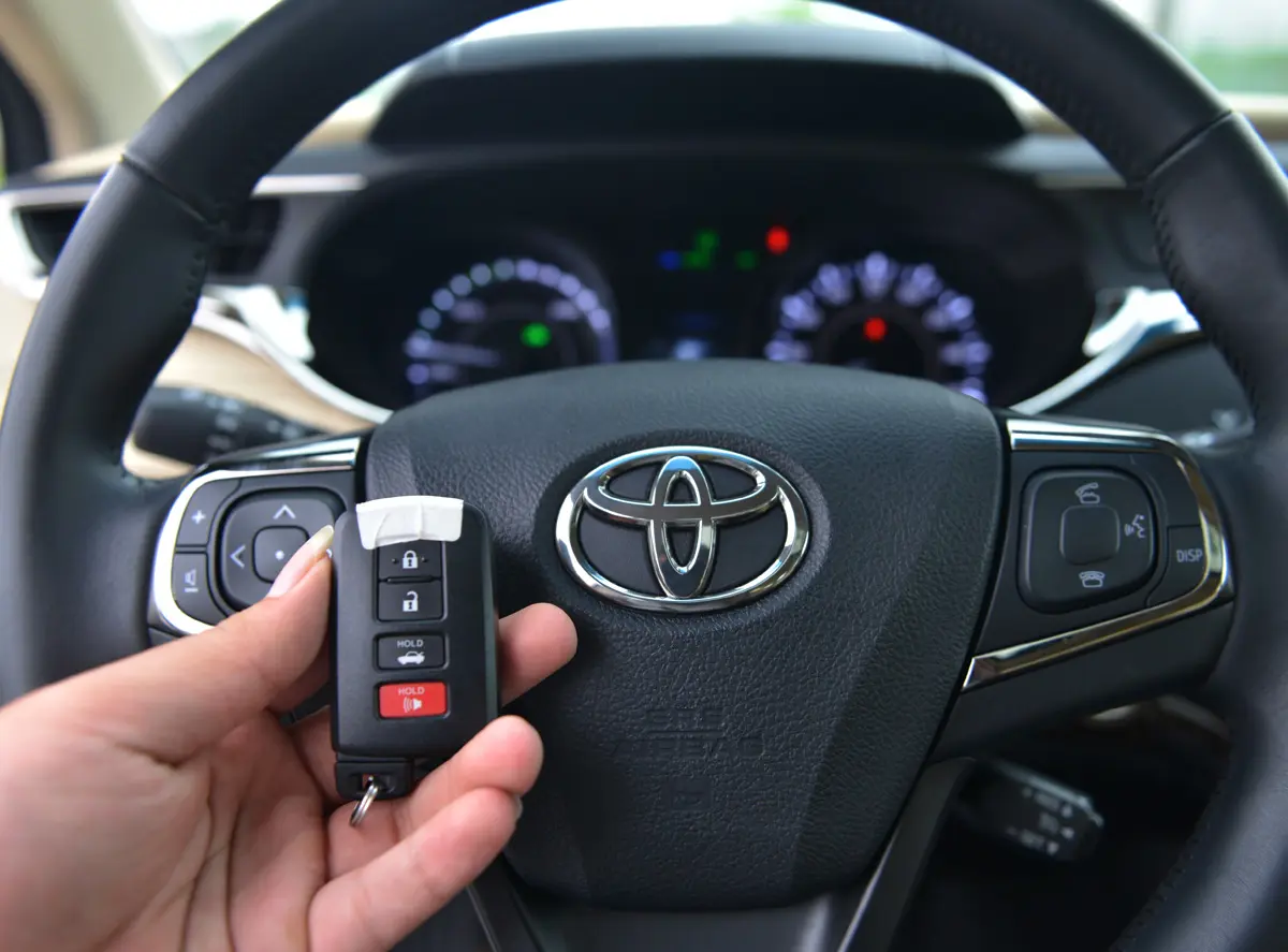 Bàn tay cầm chìa khóa thông minh trước vô lăng Toyota Avalon
