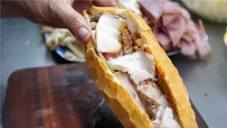 Bàn tay cầm ổ bánh mì kẹp thịt và pate