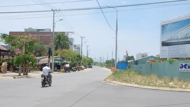 Con đường ven khu đất dự án với hàng rào tôn và biển quảng cáo