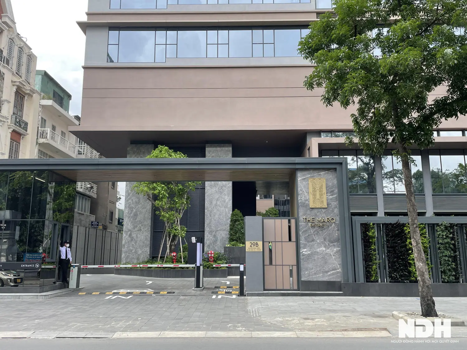 Cổng vào một dự án căn hộ với hàng rào và cây xanh