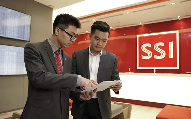 Hai nhân viên SSI trao đổi tài liệu trước bảng hiệu công ty