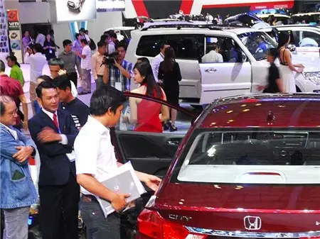 Khách xem xe tại một triển lãm ô tô, nhân viên bán hàng tư vấn bên cạnh