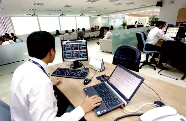 Nhân viên môi giới làm việc trước nhiều màn hình bảng giá