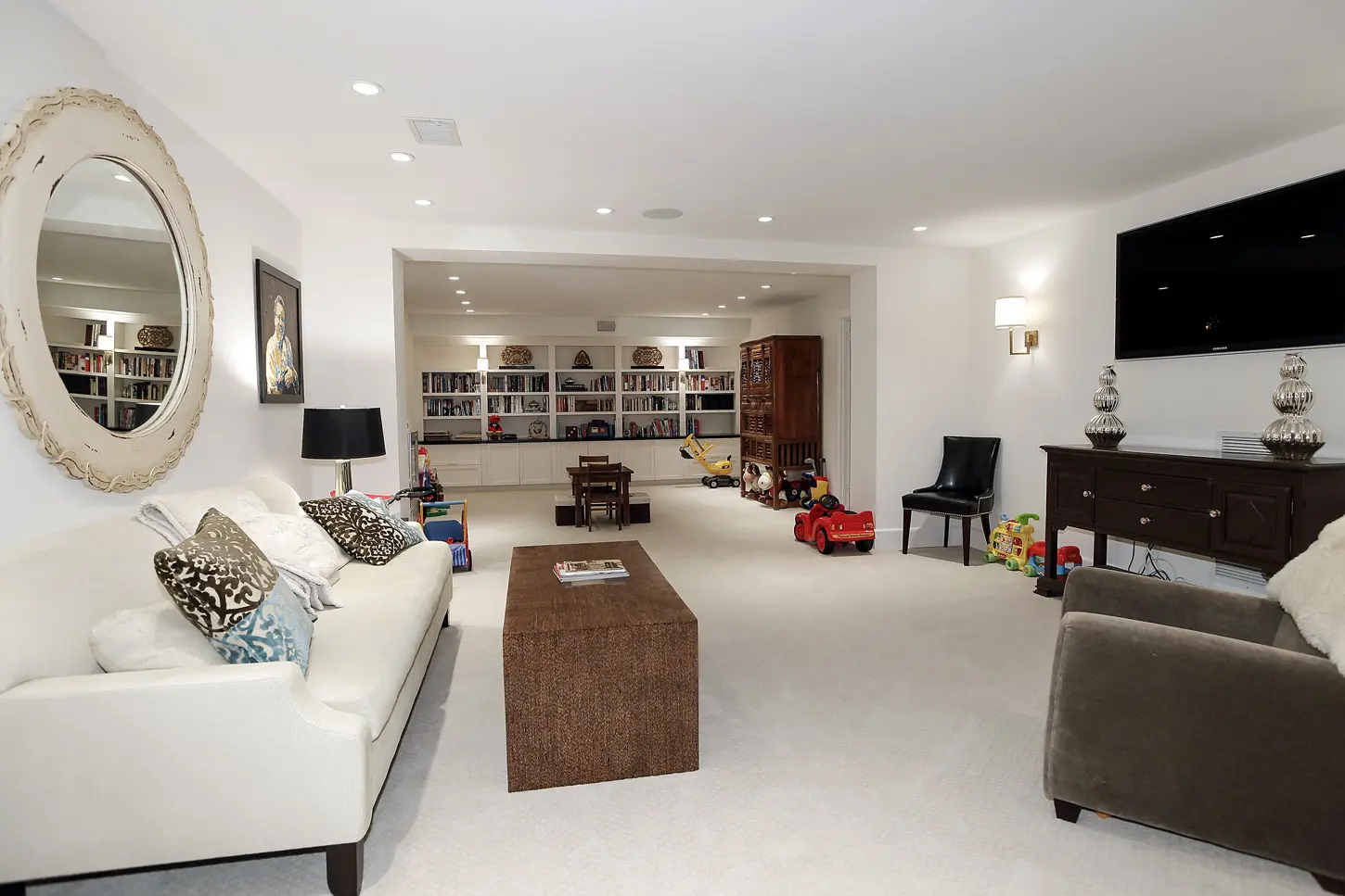 Phòng sinh hoạt rộng màu trắng với sofa dài và kệ sách âm tường