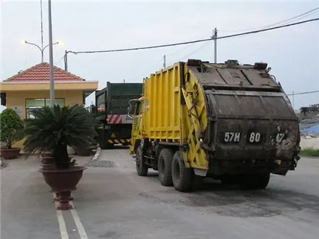 Xe ép rác màu vàng chạy vào khu xử lý rác