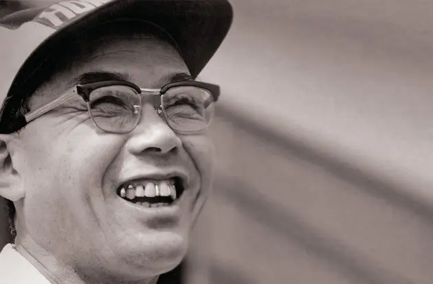 Ảnh đen trắng Soichiro Honda đội mũ, đeo kính cười rạng rỡ