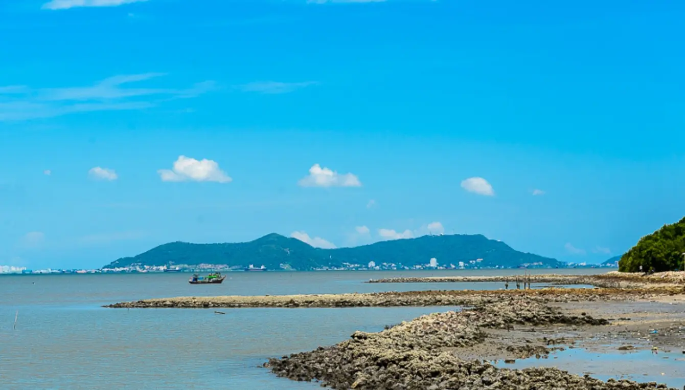 Bờ biển đá ngầm nhìn ra hòn đảo phía xa dưới trời xanh