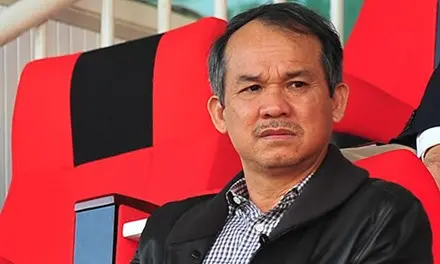 Chân dung người đàn ông mặc áo khoác đen ngồi trên ghế đỏ