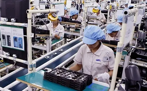 Công nhân đội mũ xanh làm việc trên dây chuyền lắp ráp điện tử