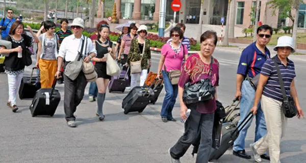 Đoàn khách du lịch kéo vali đi bộ trên đường