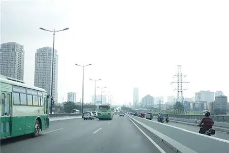 Đường cao tốc rộng có xe buýt, các cao ốc ở phía xa