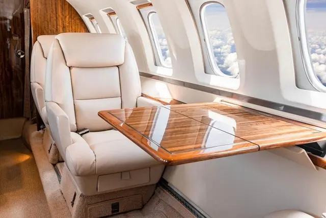 Ghế da màu kem và bàn gỗ trong cabin máy bay