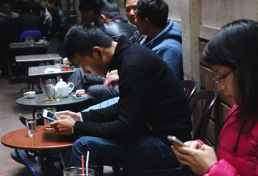 Giới trẻ ngồi quán cà phê vỉa hè, mải mê dùng điện thoại