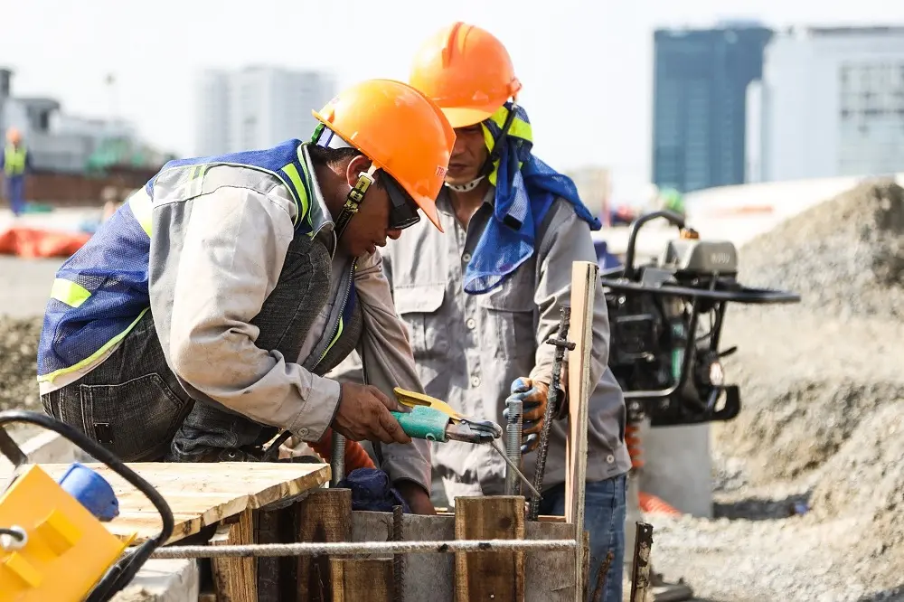 Hai công nhân đội mũ cam thao tác thiết bị