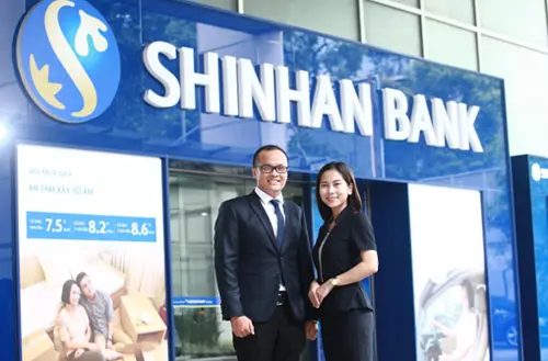 Hai nhân viên mặc vest đứng trước trụ sở Shinhan Bank