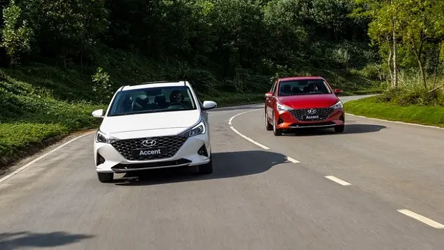 Hai xe Hyundai Accent trắng và đỏ chạy trên đường đèo