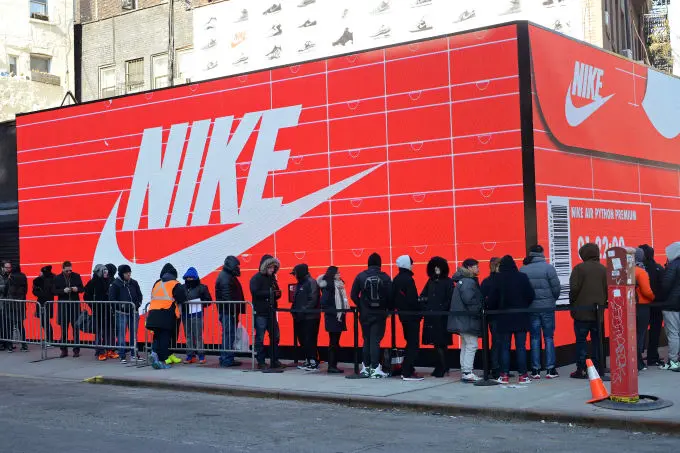 Hàng người xếp hàng trước bức tường quảng cáo Nike màu đỏ