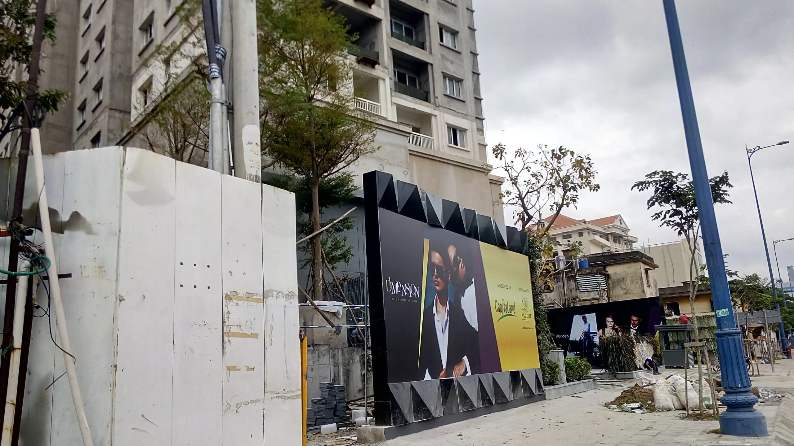 Hàng rào tôn quây khu đất dự án trên phố, phía sau là chung cư đang xây