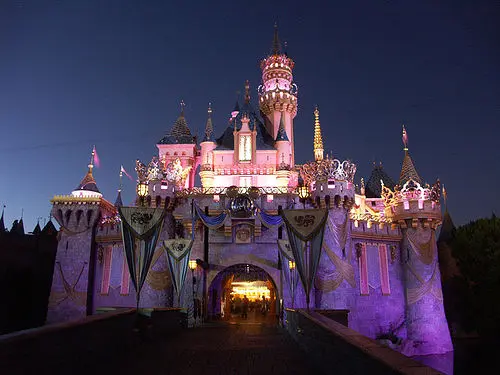 Lâu đài công viên Disneyland rực sáng ánh đèn tím hồng về đêm