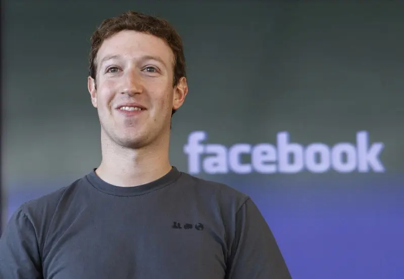 Mark Zuckerberg mặc áo phông xám trước logo Facebook