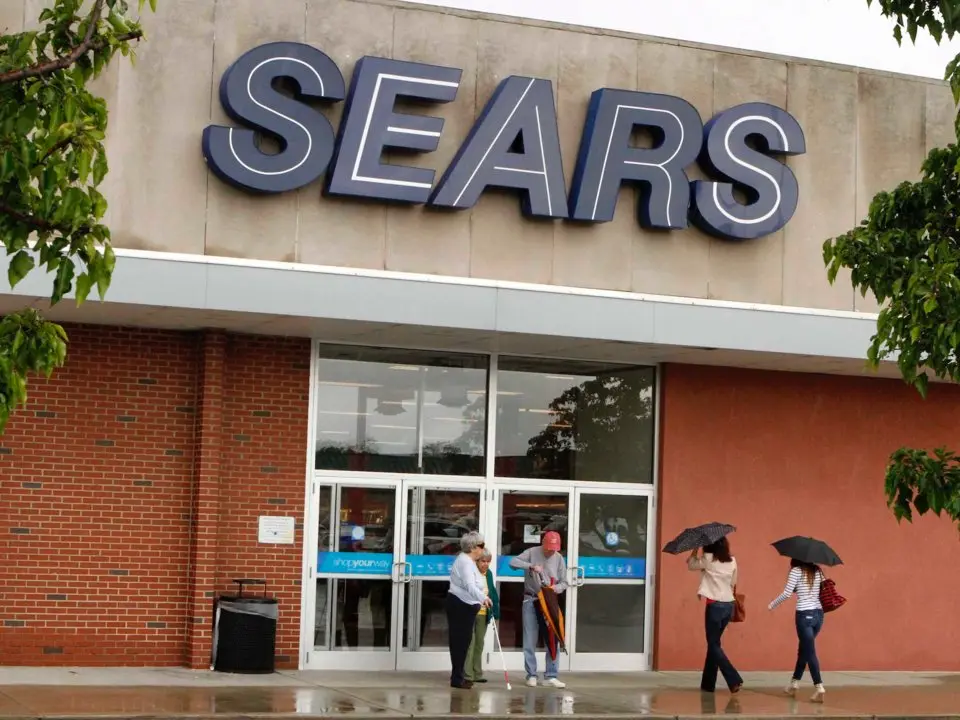 Mặt tiền cửa hàng Sears, người đi đường cầm ô dưới mưa