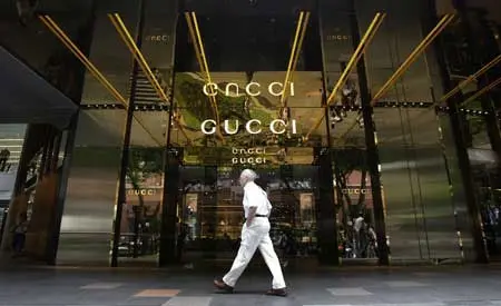 Người đàn ông mặc đồ trắng đi ngang cửa hàng Gucci