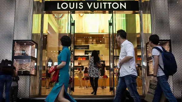 Người đi bộ ngang qua cửa hàng Louis Vuitton sáng đèn