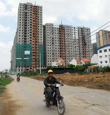 Người đi xe máy trên đường đất trước các chung cư đang xây