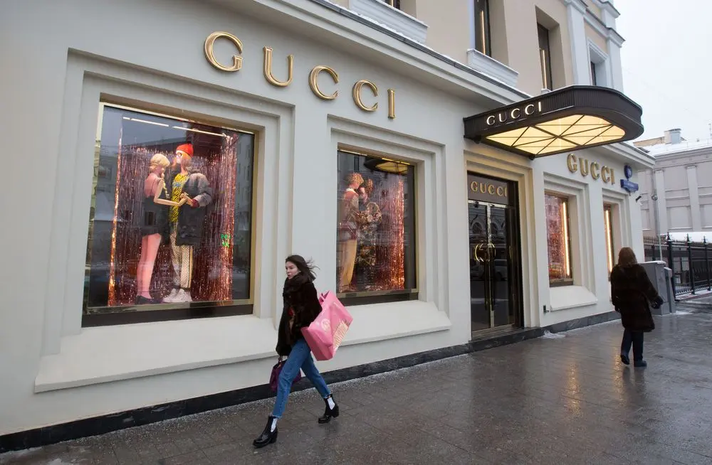 Người phụ nữ cầm túi hồng đi ngang cửa hàng Gucci