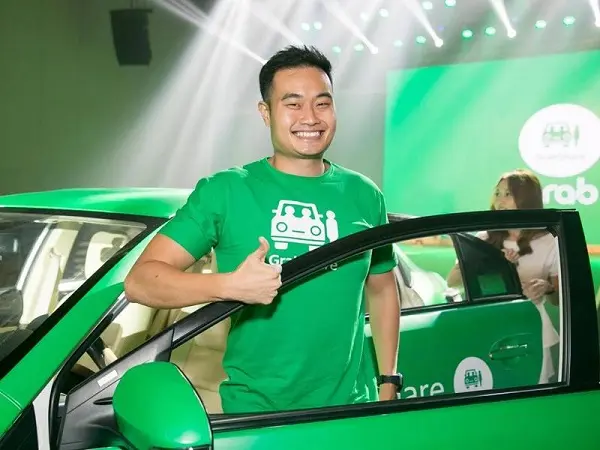 Ông Jerry Lim mặc áo xanh Grab đứng cạnh ô tô