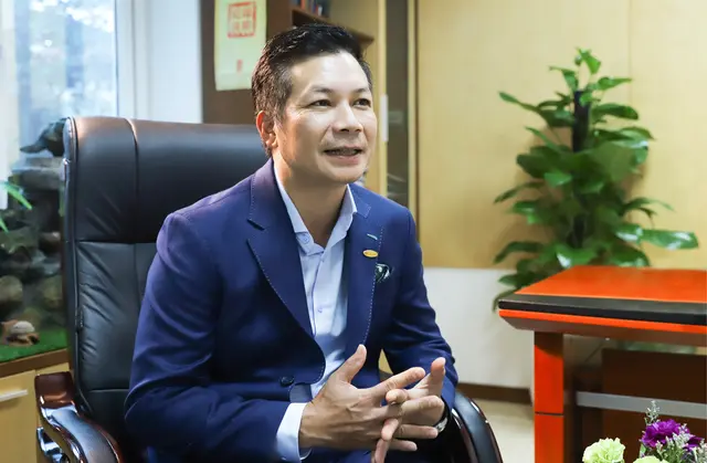 Ông Phạm Thanh Hưng mặc vest xanh ngồi trả lời phỏng vấn trong văn phòng