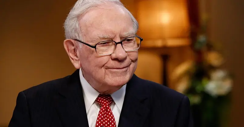 Warren Buffett đeo kính, thắt cà vạt đỏ mỉm cười