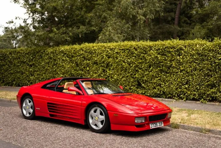 Xe Ferrari 348 mui trần màu đỏ bên hàng rào cây