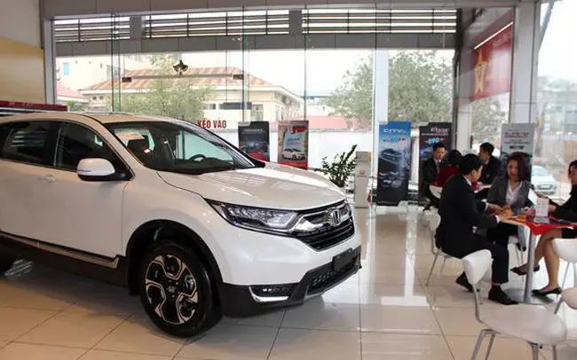 Xe Honda CR-V màu trắng trưng bày trong showroom có khách ngồi