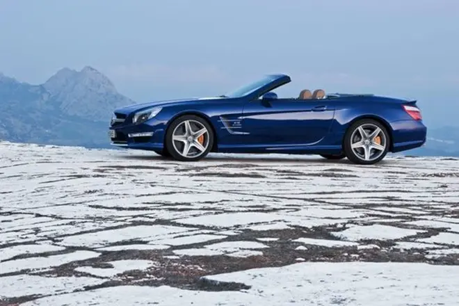 Xe Mercedes mui trần màu xanh đỗ trên nền đá